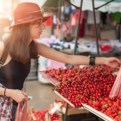 A young woman buying fruits and vegetables at a weekly market. Healthy diet