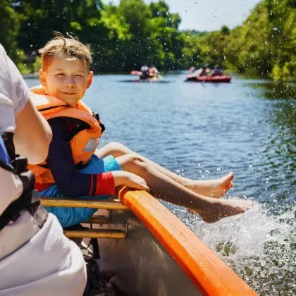 A happy child boating in summer. Splashes of water on a boat tour.